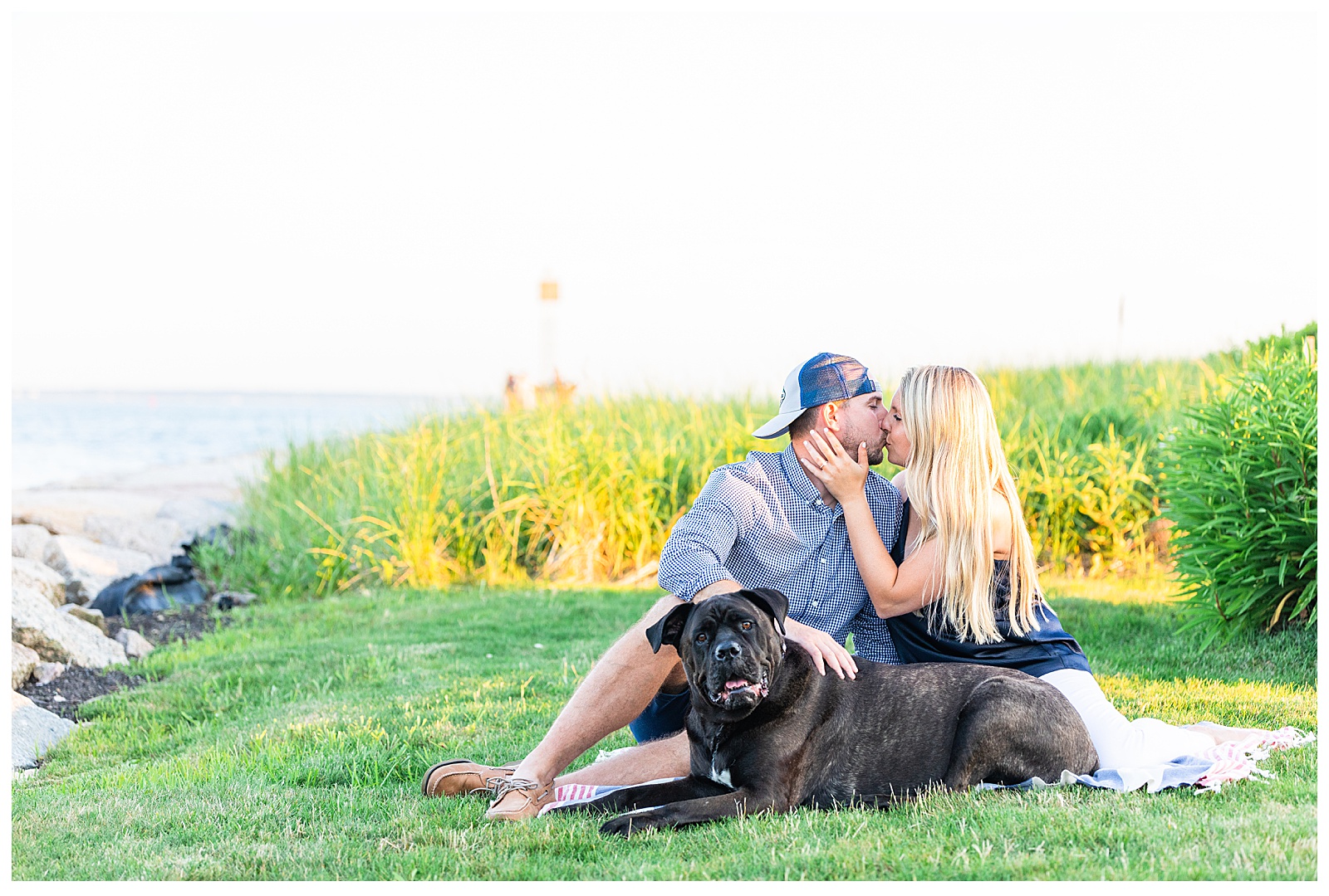 couples sitting on blanket kissing with dog looking at camera